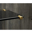 Smoked glass shelf held by brass clamps on its cables against grey timber panelling
